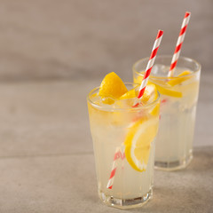 two glass of lemonade with lemons and lime and straw, on a dark background, with space, a cool drink and summer mood