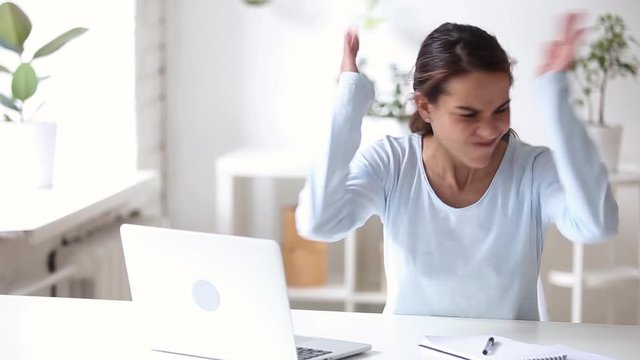 Woman sitting at desk having problems with notebook feels angry