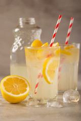 two glasses of lemonade with lemons and lime and straw, a bottle with a cool drink and summer mood, with ice, freshness in hot summer
