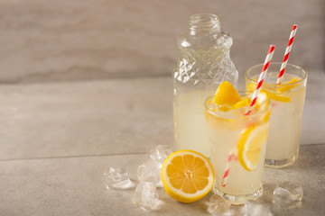 two glasses of lemonade with lemons and lime and straw, a bottle with a cool drink and summer mood, with ice, freshness in hot summer