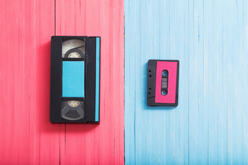Video cassette and tape cassette on pink and blue wooden backgro