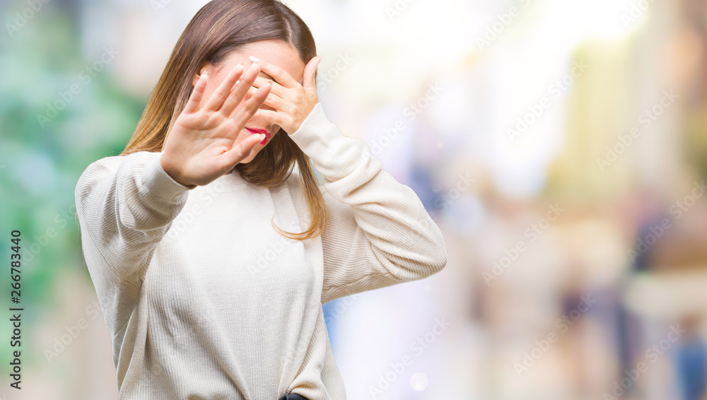 Poster Young beautiful woman casual white sweater over isolated background covering eyes with hands and doing stop gesture with sad and fear expression. Embarrassed and negative concept.