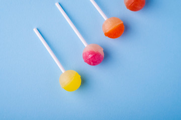 Lollipop candies in diagonal row on blue background top view
