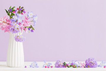 blue and pink flowers in vase on white table