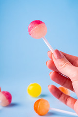 Woman holding in hand lollipop candy on blue background