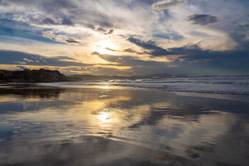 Fototapeta na wymiar sunset on the beach of Atxabiribil, Sopelana, vizcaya. The sun is reflected on the seashore