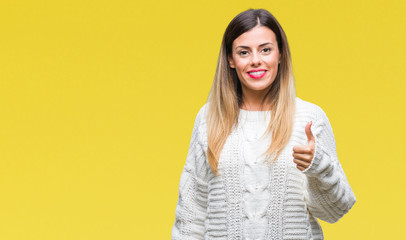 Fototapeta premium Young beautiful woman casual white sweater over isolated background doing happy thumbs up gesture with hand. Approving expression looking at the camera with showing success.