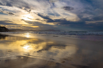 Naklejka na ściany i meble sunset on the beach of Atxabiribil, Sopelana, vizcaya. The sun is reflected on the seashore