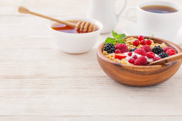 granola with berries on white wooden background