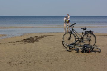 Happy couple left their bicycles on the beach, which they have ridden from holiday accommodation.