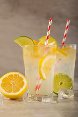 two glasses of lemonade with lemons and lime and straw, a cool drink and summer mood, with ice