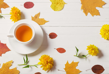 cup of tea with autumn leaves on wooden background