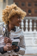 Young Black Stylish Woman Walking On The City Street  With A Smartphone