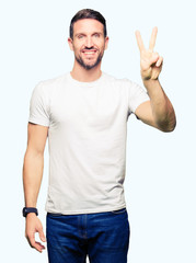 Fototapeta premium Handsome man wearing casual white t-shirt showing and pointing up with fingers number two while smiling confident and happy.