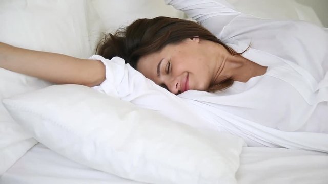 Woman wakes up raise stretches hands in bed feels healthy