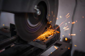 Cutting metal with grinder in workshop. Sparks while grinding iron. Cutting machine