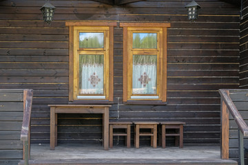 Obraz na płótnie Canvas wooden brown facade of a vintage house with two Windows. wooden table and stools against the wal