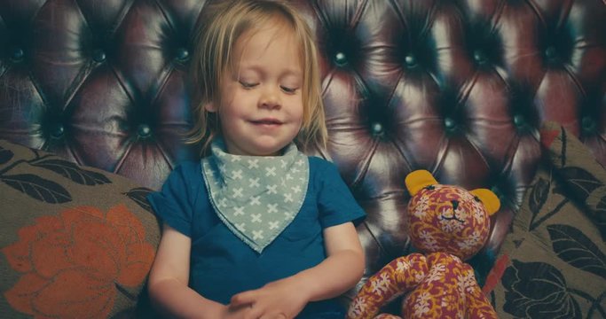 Little toddler sitting on sofa with his stuffed bear