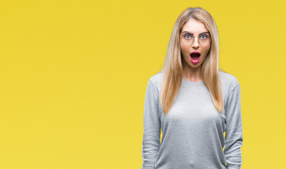 Young beautiful blonde woman wearing glasses over isolated background afraid and shocked with...