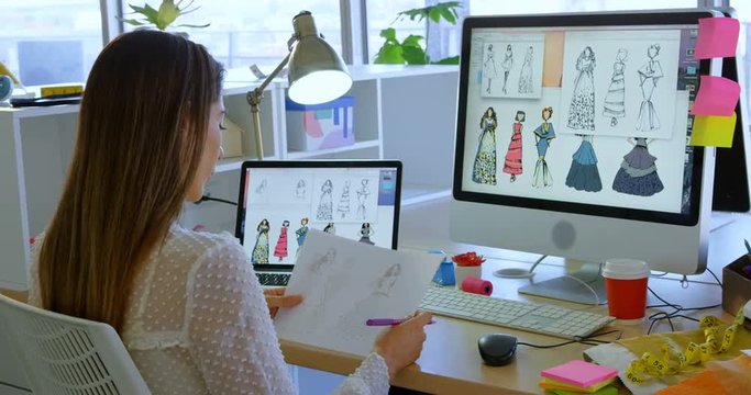 Rear view of Caucasian female fashion designer working on computer at desk in office 4k