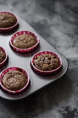 Yummy chocolate muffins in baking tin on dark gray background