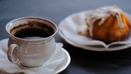 A Cup of coffee and a fresh cake on a saucer. Morning invigorating drink in a cafe or restaurant. Beautiful delicate photo for romanticism.