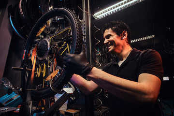 Fototapeta na wymiar Diligent attractive mechanic is fixing bicycle at his own workshop.