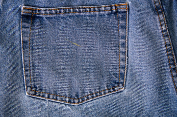 close up of back pocket on pair of old faded blue jean denim.