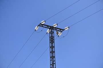 Three old power lines with a glass connection in front of a blue sky.