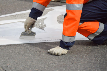 Fototapeta na wymiar Road worker makes white paint