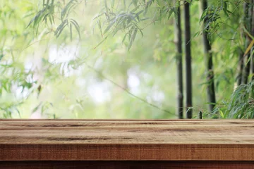 Schilderijen op glas Lege houten en vage natuur bamboe bos achtergrond. © Ubonwan