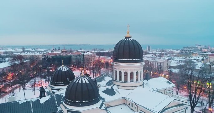 Cinematic aerial view of dome and orthodox cross on spire of Transfiguration Cathedral in Odessa on winter evening.