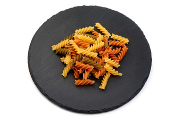 Pasta Fusilli tricolore on a slate shale plate, Itallian food, close-up, isolated on white background