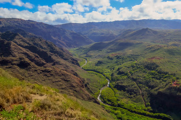 River running through green valley and mountain landscape at Waimea Canyon State Park, Kauai, Hawaii, USA