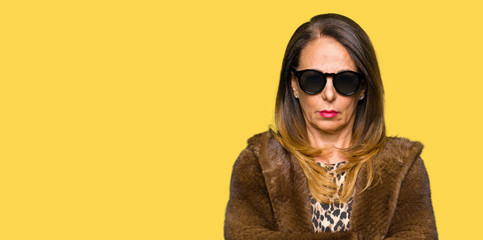 Beautiful middle age elegant woman wearing sunglasses and mink coat skeptic and nervous,...