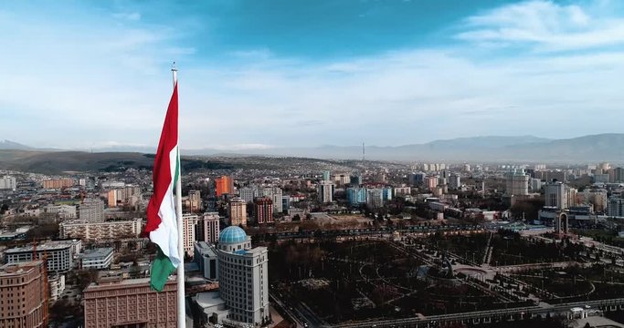 Flag of Tajikistan on flagpole against the blue sky modern toning