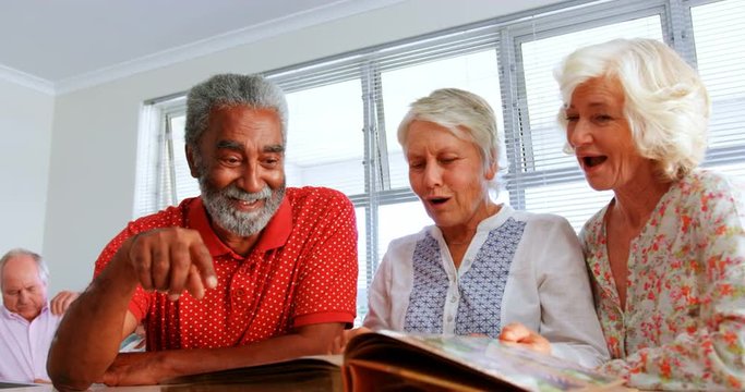 Front view of active senior diverse people looking at photo album in nursing home 4k