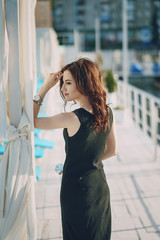 A beautiful young girl with curly hair and glasses standing by the water