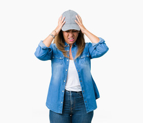 Beautiful middle age woman wearing sport cap over isolated background suffering from headache desperate and stressed because pain and migraine. Hands on head.