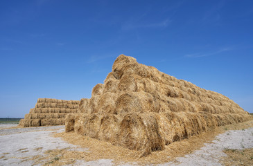 Big haystack from round bales laid in the form of a pyramid against the blue sky