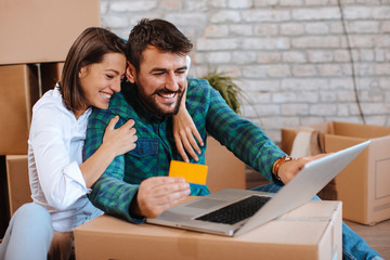 Young happy couple buying over the Internet in a new home