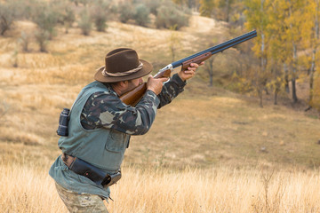 Hunter with a hat and a gun in search of prey in the steppe	