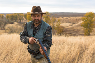 Hunter with a hat and a gun in search of prey in the steppe	