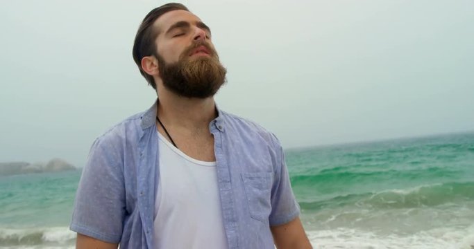 Front view of Caucasian man standing with eye closed on the beach 4k