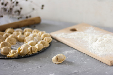 Homemade ravioli on a round platter on the table with flour and rolling pin