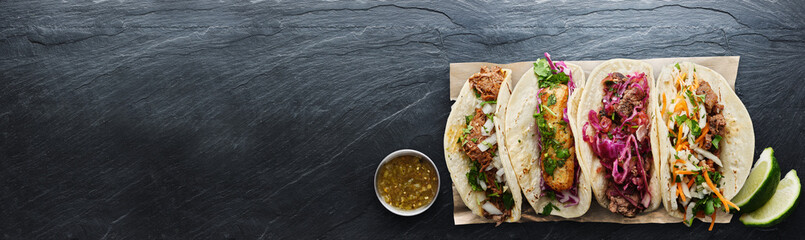 four mexican street tacos with fish barbacoa and carnitas shot in panoramic composition
