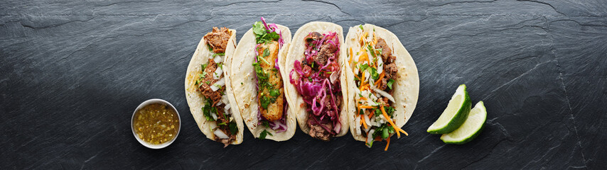 four mexican street tacos with fish barbacoa and carnitas shot in panoramic composition
