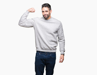 Young handsome man wearing sweatshirt over isolated background Strong person showing arm muscle, confident and proud of power