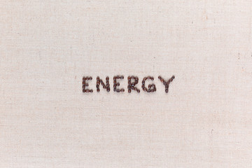 Energy word made from coffee beans on linen texture aligned centered.