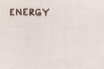 Energy word made from coffee beans on linen texture aligned top left.
